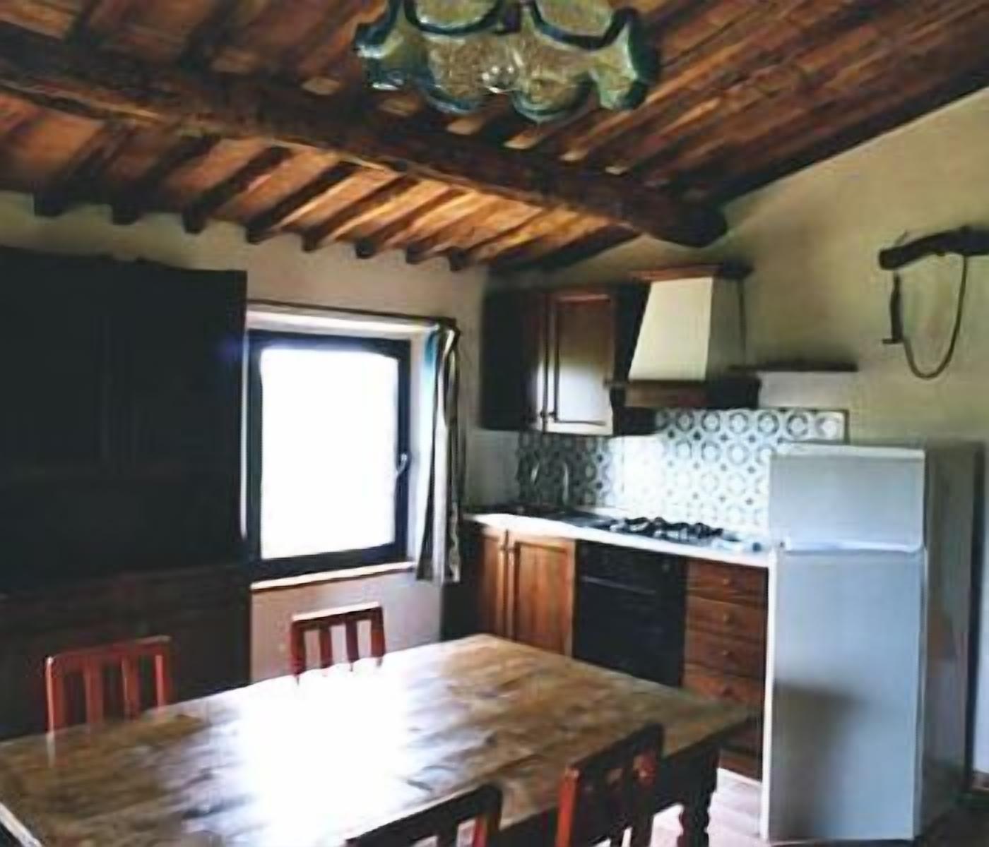Una cocina con armarios de madera, una mesa de comedor y un refrigerador.