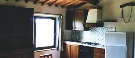 Una cocina con armarios de madera, una mesa de comedor y un refrigerador.