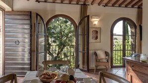 A dining area with a table set for breakfast, including croissants and fruit, and a view of greenery through arched windows. - Borgo al Cerro (Casole d'Elsa)