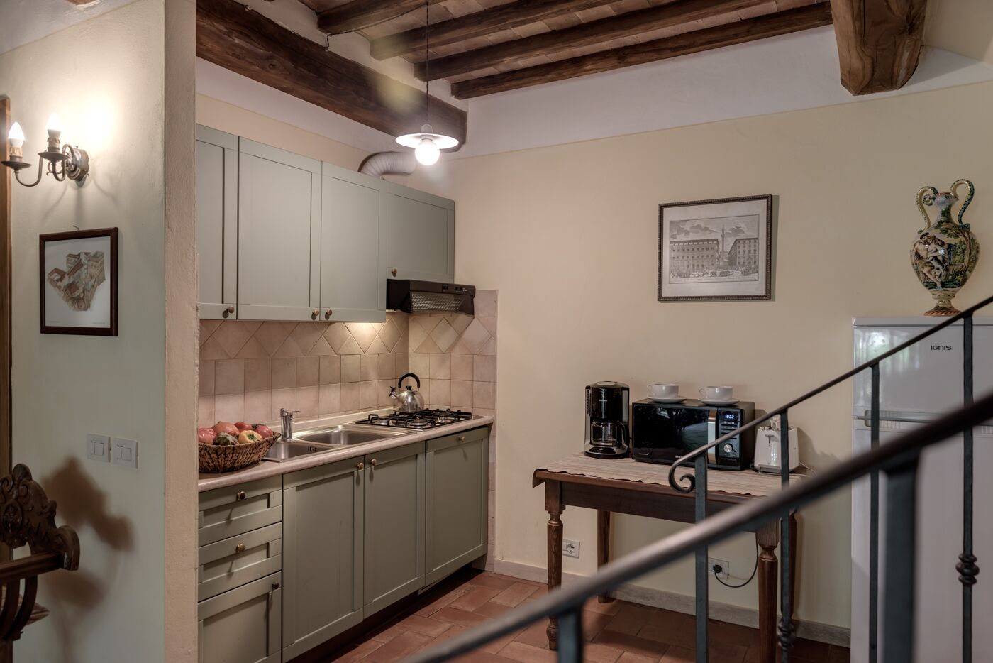 Una cocina con gabinetes verde claro, una estufa a gas, una cafetera y un microondas.