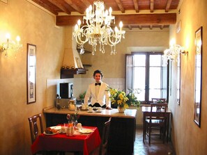 Un comedor con una araña, un chef con chaqueta blanca y un mantel rojo.