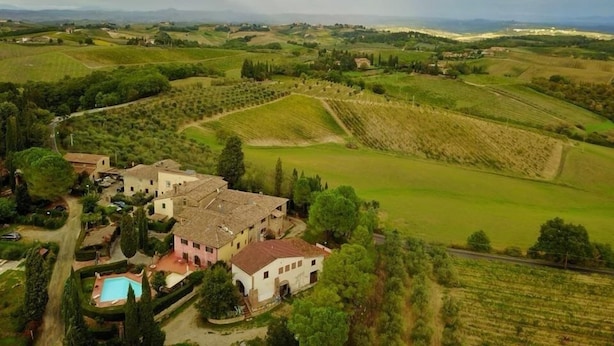 Vue aérienne d’un domaine rural comprenant une grande maison, une piscine et de vastes champs.