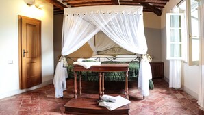Une chambre dotée d’un lit à baldaquin, d’une table en bois recouverte d’une nappe blanche et d’un banc en bois.
