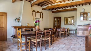 Un coin repas avec une table et des chaises en bois, une cheminée en briques et un plafond en bois.