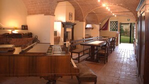 Ein Restaurant mit Backsteinbögen, Holztischen und einem Klavier.