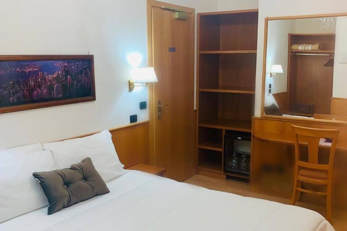 Una habitación de hotel con una cama grande, un escritorio, un armario y una araña.