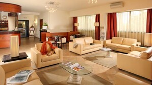 A spacious hotel lobby with a reception desk, seating area with sofas and a coffee table, and large windows with curtains. - Cassia Hotel (Rome)