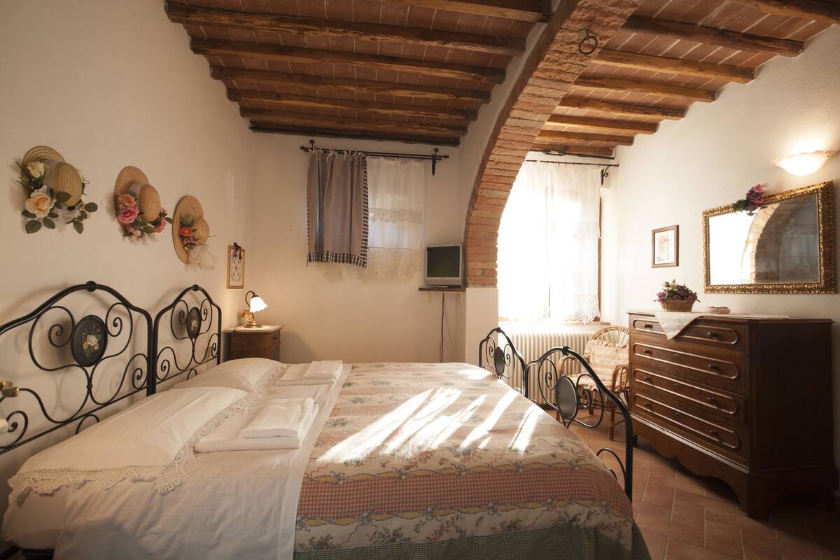 Un dormitorio con cama, cómoda, espejo y ventana con cortinas.