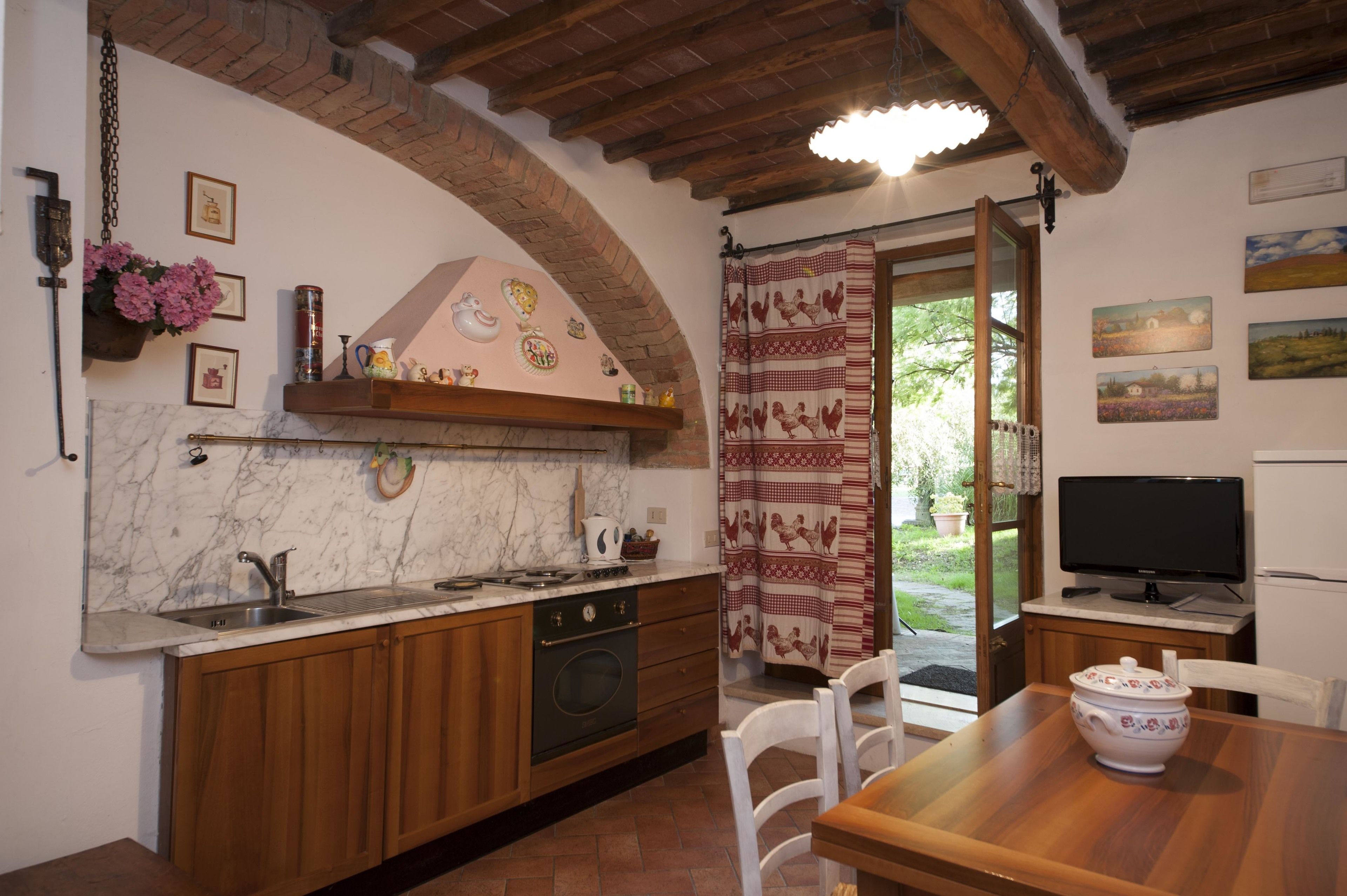 A kitchen with wooden cabinets, a marble backsplash, a built-in oven, and a dining area with a table and chairs.