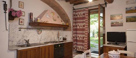 A kitchen with wooden cabinets, a marble backsplash, a built-in oven, and a dining area with a table and chairs.