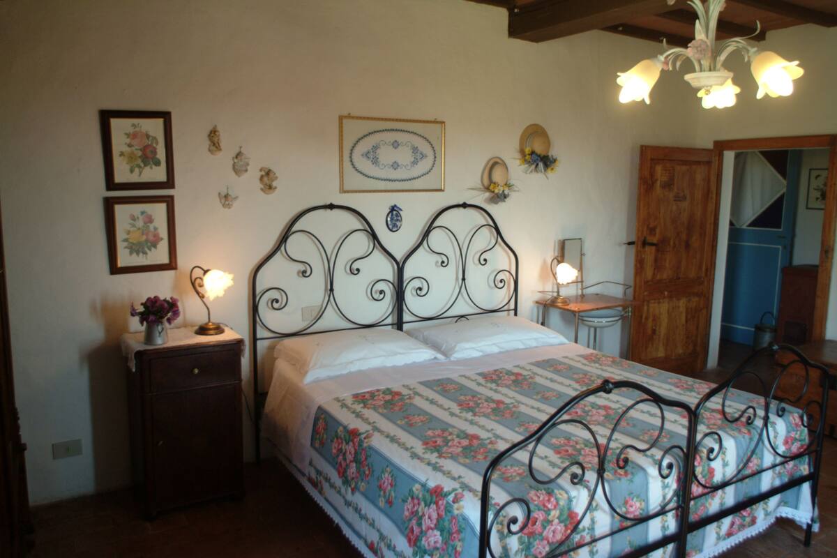 Un dormitorio con cama, mesita de noche y adornos en la pared.