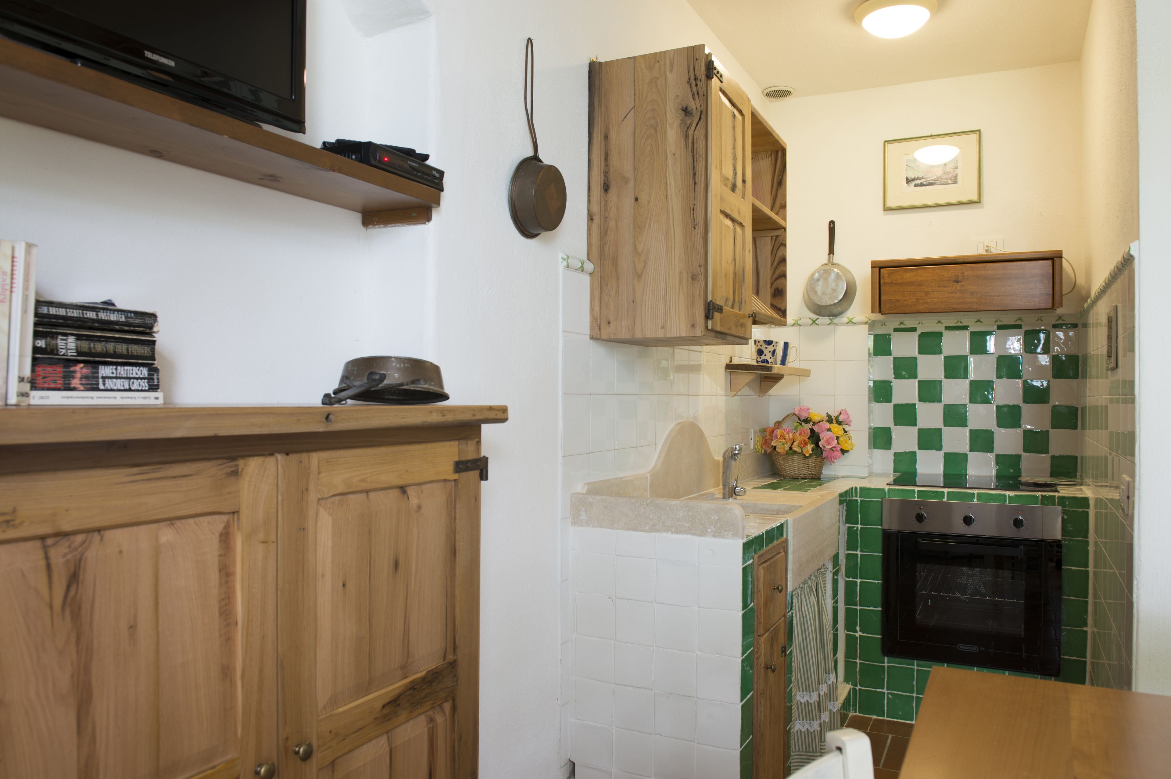 Eine Küche mit Holzausbau, einem schwarzen Backofen und einer gefliesten Spritzschutzwand.