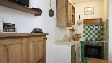 Eine Küche mit Holzausbau, einem schwarzen Backofen und einer gefliesten Spritzschutzwand.