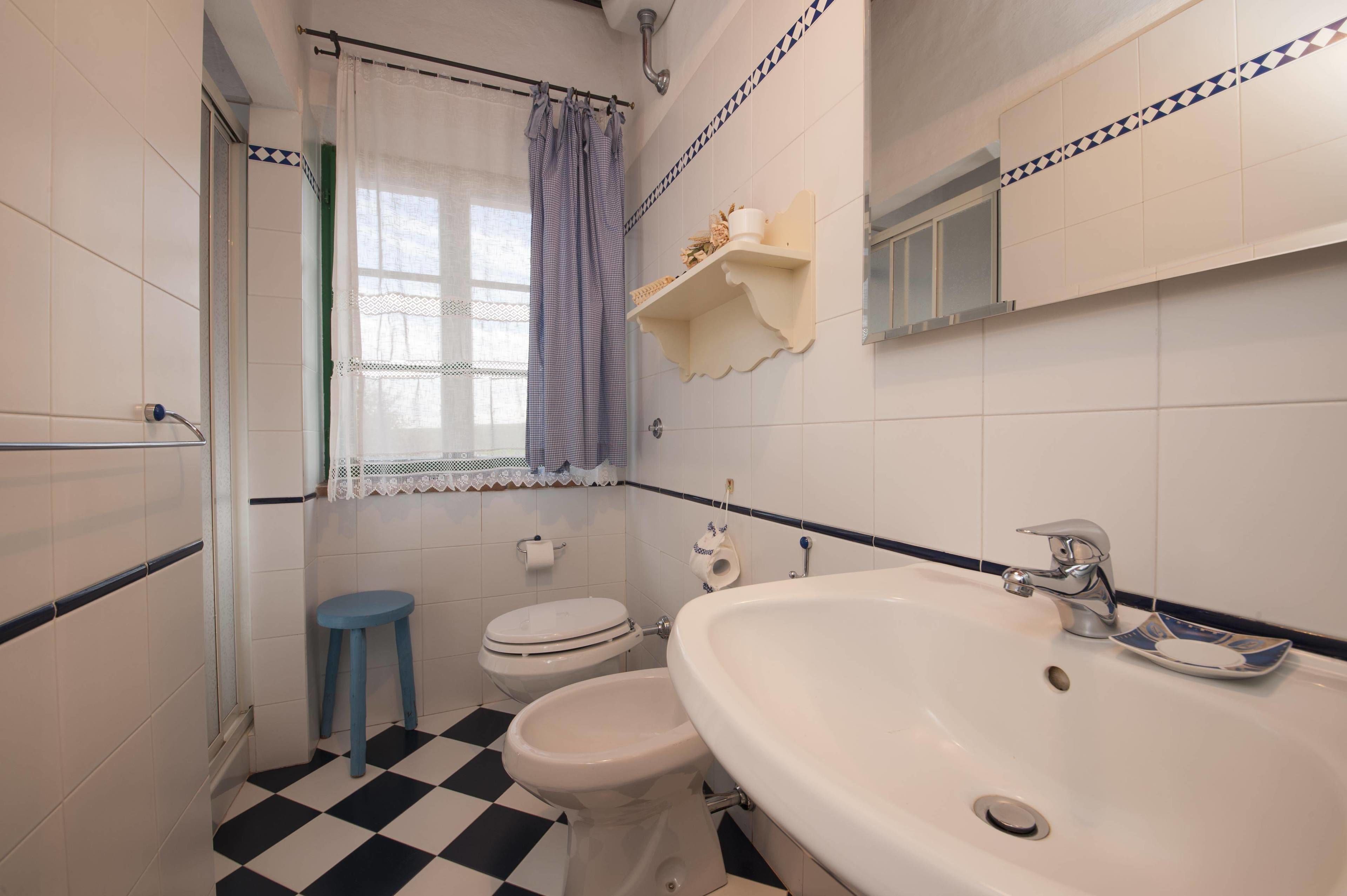 A bathroom with a checkered floor, a sink, a toilet, and a shower area.