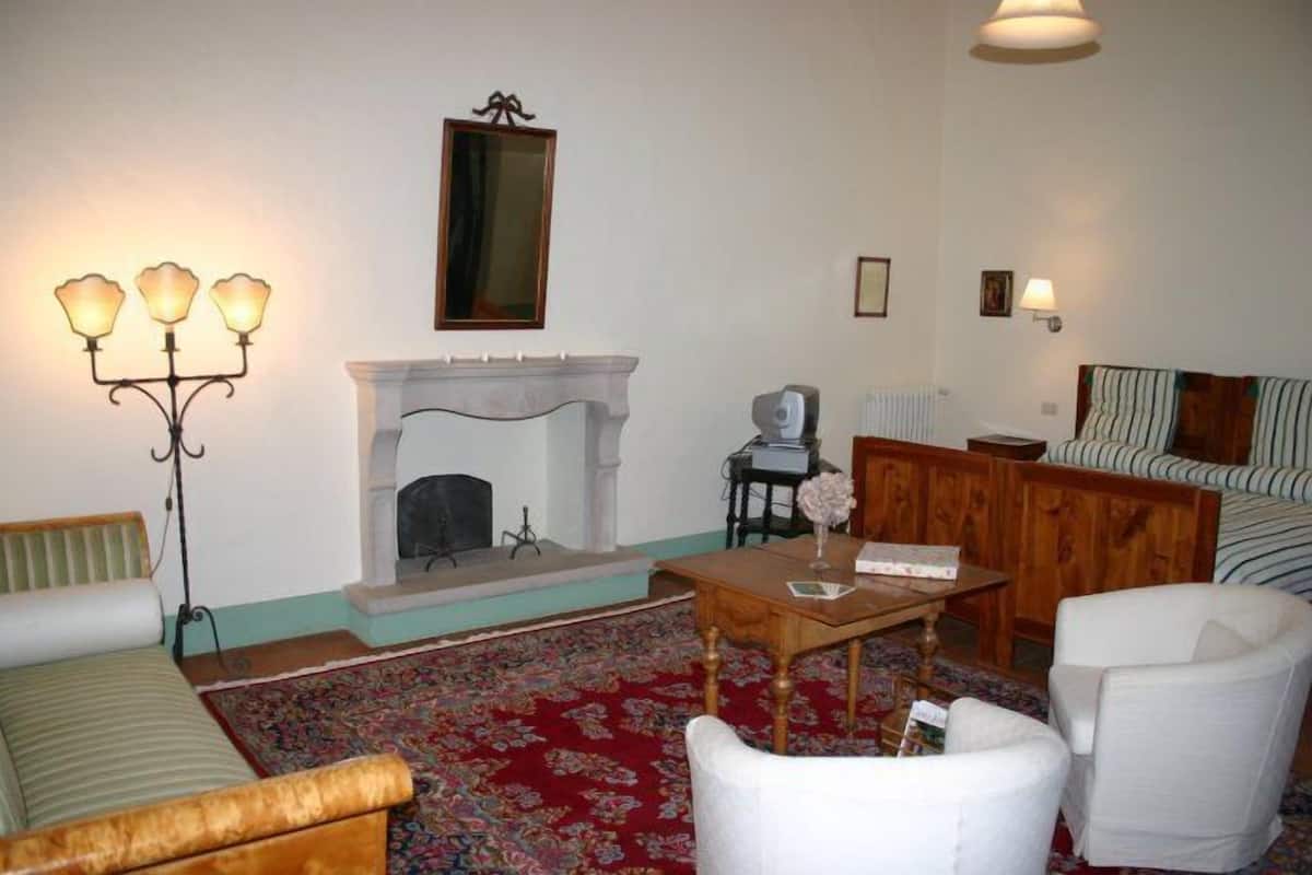 Un salon chaleureux avec une cheminée, un canapé, une table basse et une tête de lit à rayures.