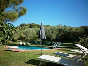 A poolside area with lounge chairs and an umbrella. - Villa Buoninsegna (Rapolano Terme)