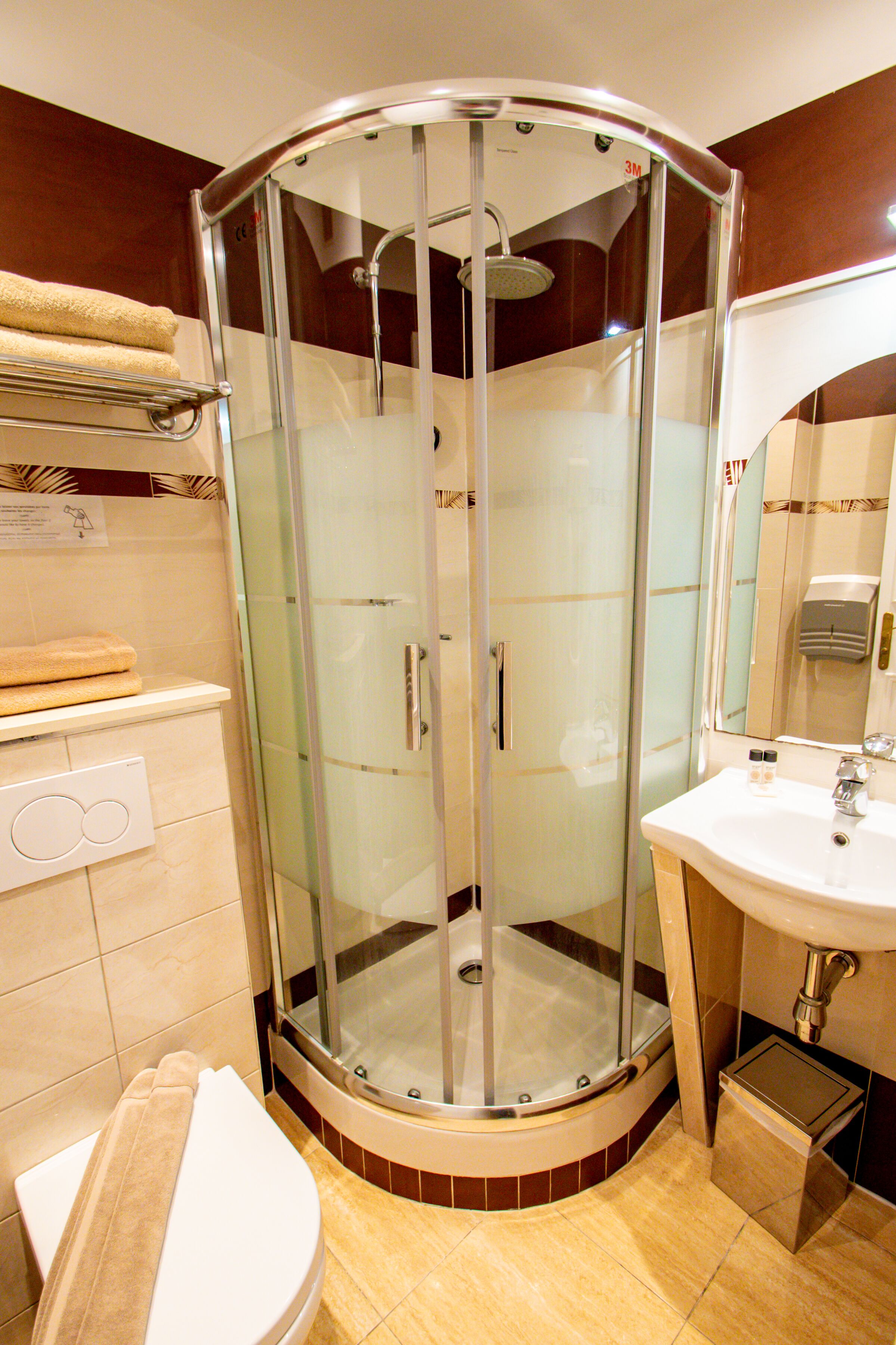 Un bagno con doccia vetrata, lavandino bianco e water.
