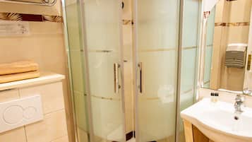 Un bagno con doccia vetrata, lavandino bianco e water.