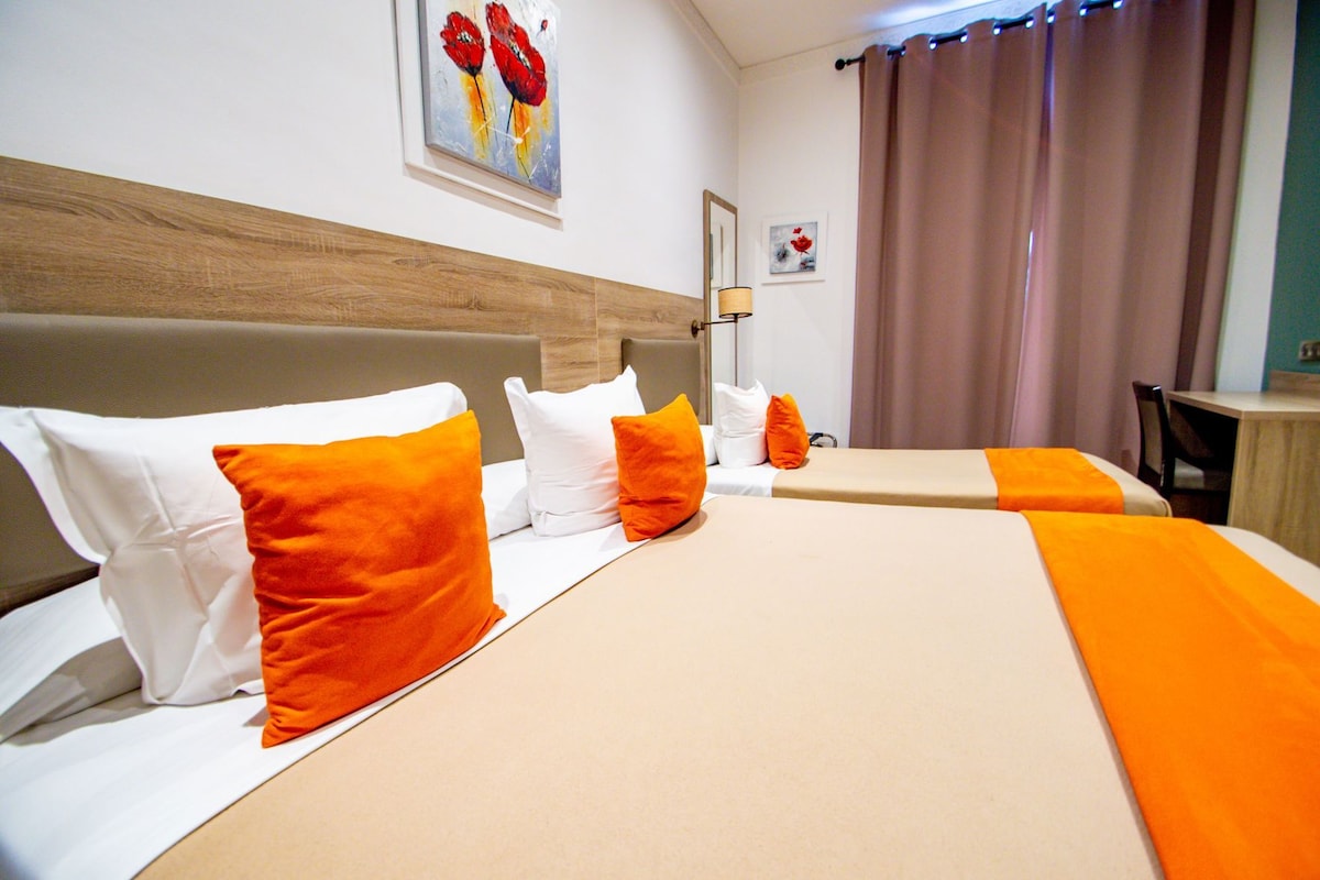 A hotel room with two beds, a wooden headboard, and a painting on the wall.