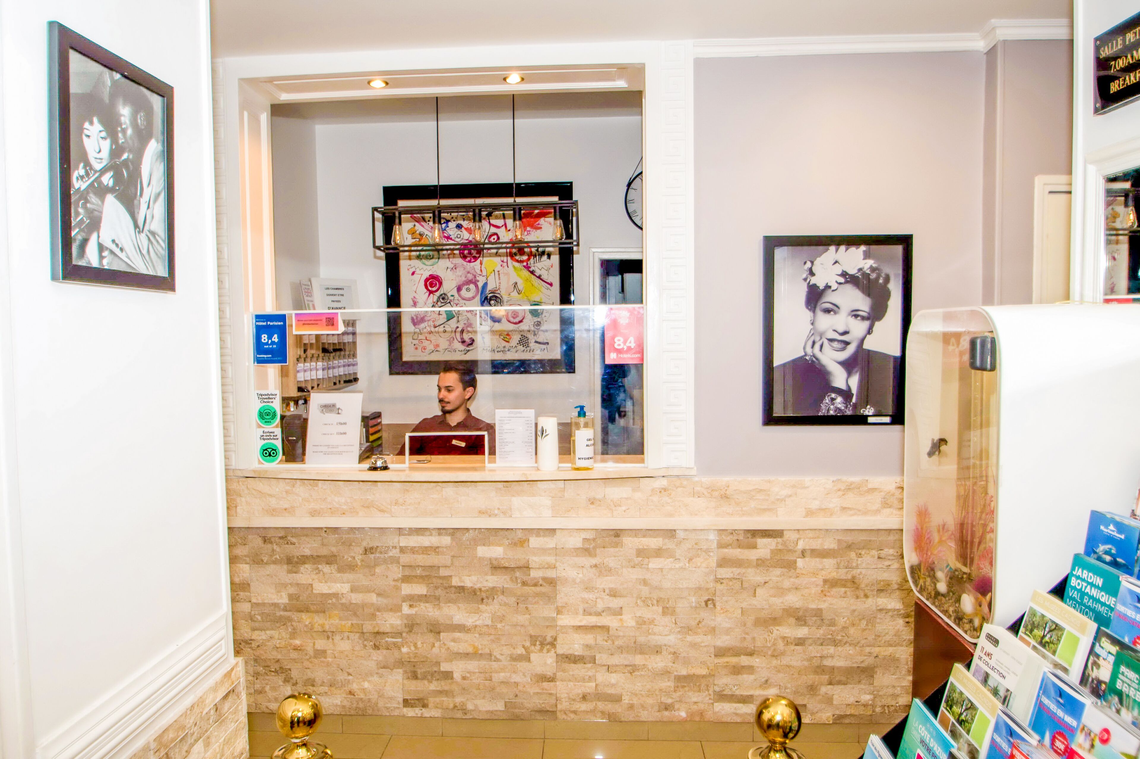 A hotel reception area with a counter, a menu board, and a wall with framed pictures.