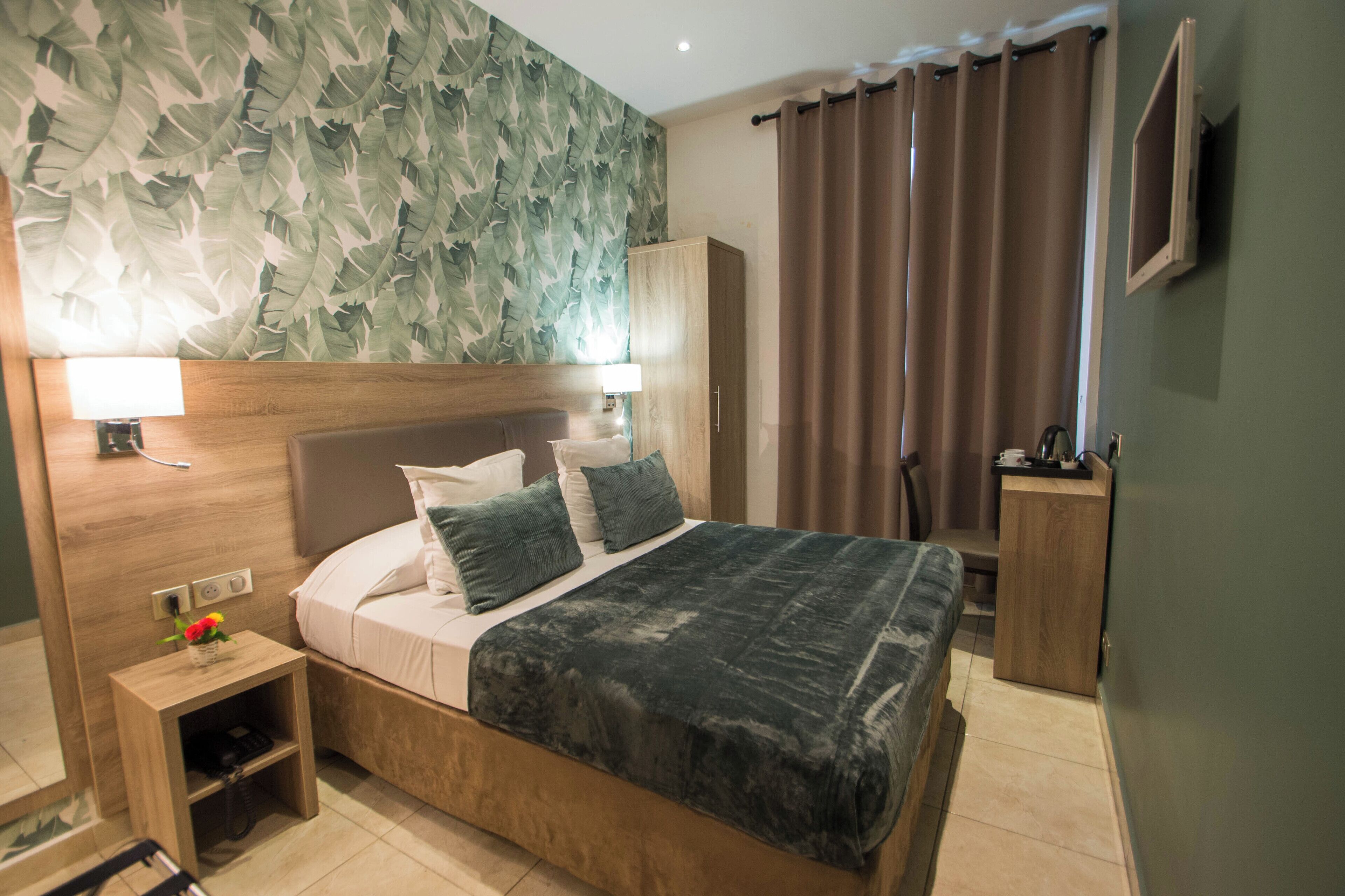 A bedroom with a bed, nightstand, wardrobe, and a wall with a leaf pattern.