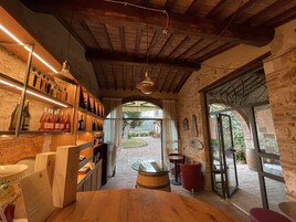 Un interior rústico con estantes de madera que exhiben botellas de vino, una mesa de vidrio y sillas rojas.