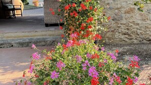 A stone building with a rustic archway, a wicker basket, and a bench. - Il Colombaio Winery and Rooms (Monteriggioni)