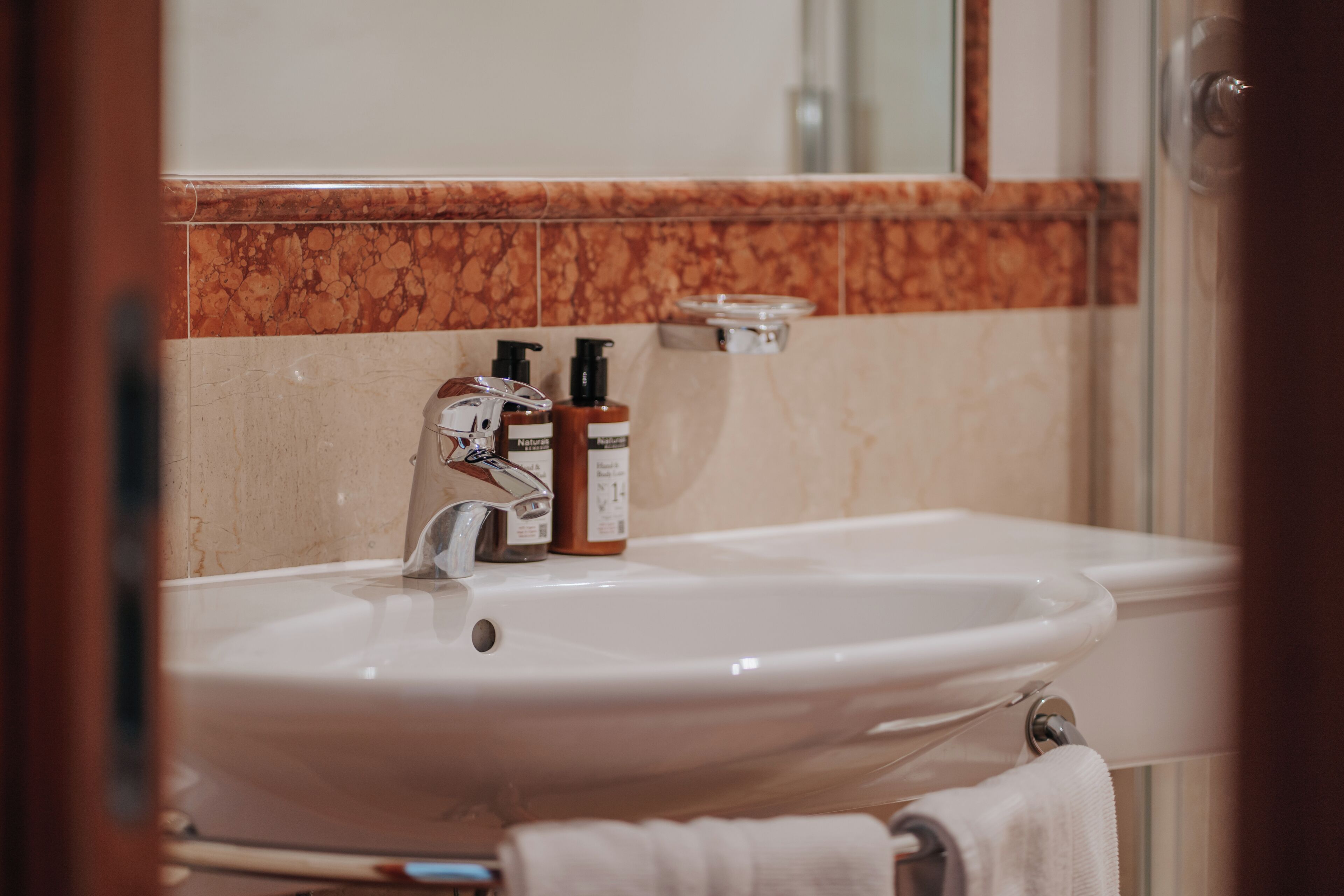 A bathroom sink with a mirror, a faucet, and two bottles of soap.
