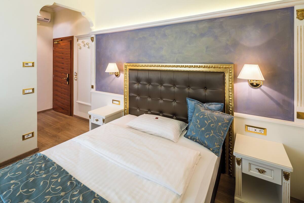 A neatly arranged bedroom with a large bed, bedside tables, and a wall-mounted lamp.