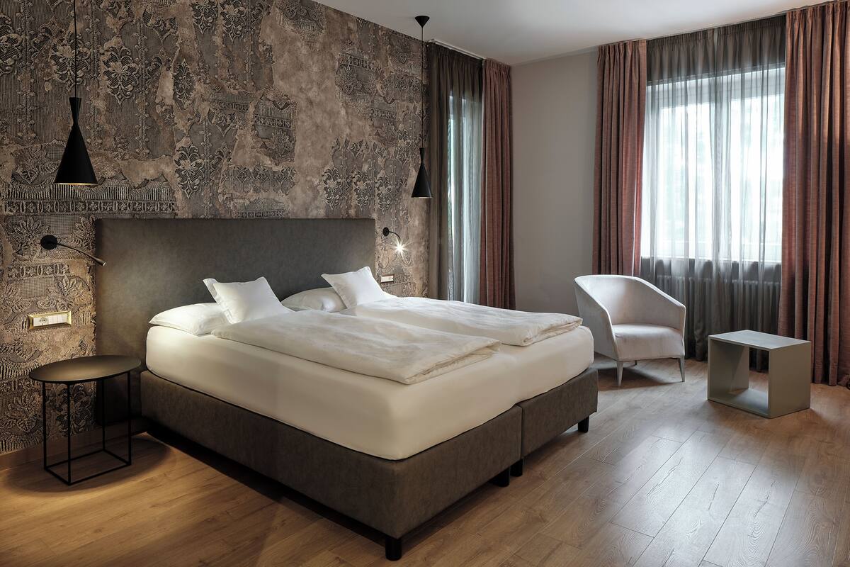 A modern bedroom with a large bed, a bedside table, a chair, and a small side table.