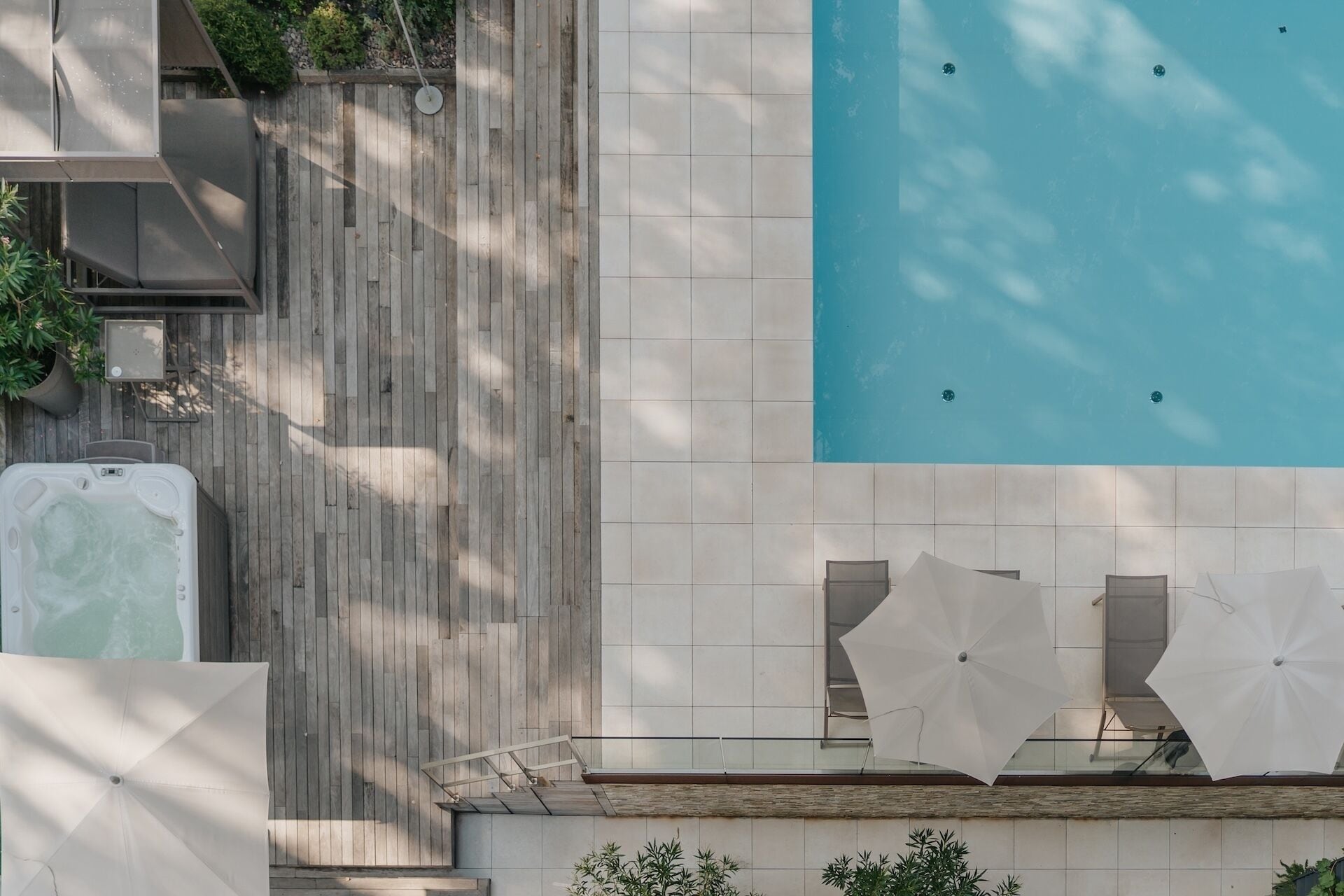 Un espace piscine aménagé sur le toit, avec une terrasse en bois, un jacuzzi et des parasols.
