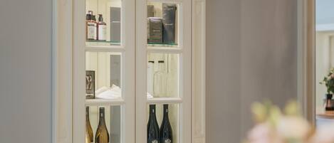 A white cabinet with glass doors containing various bottles and items.