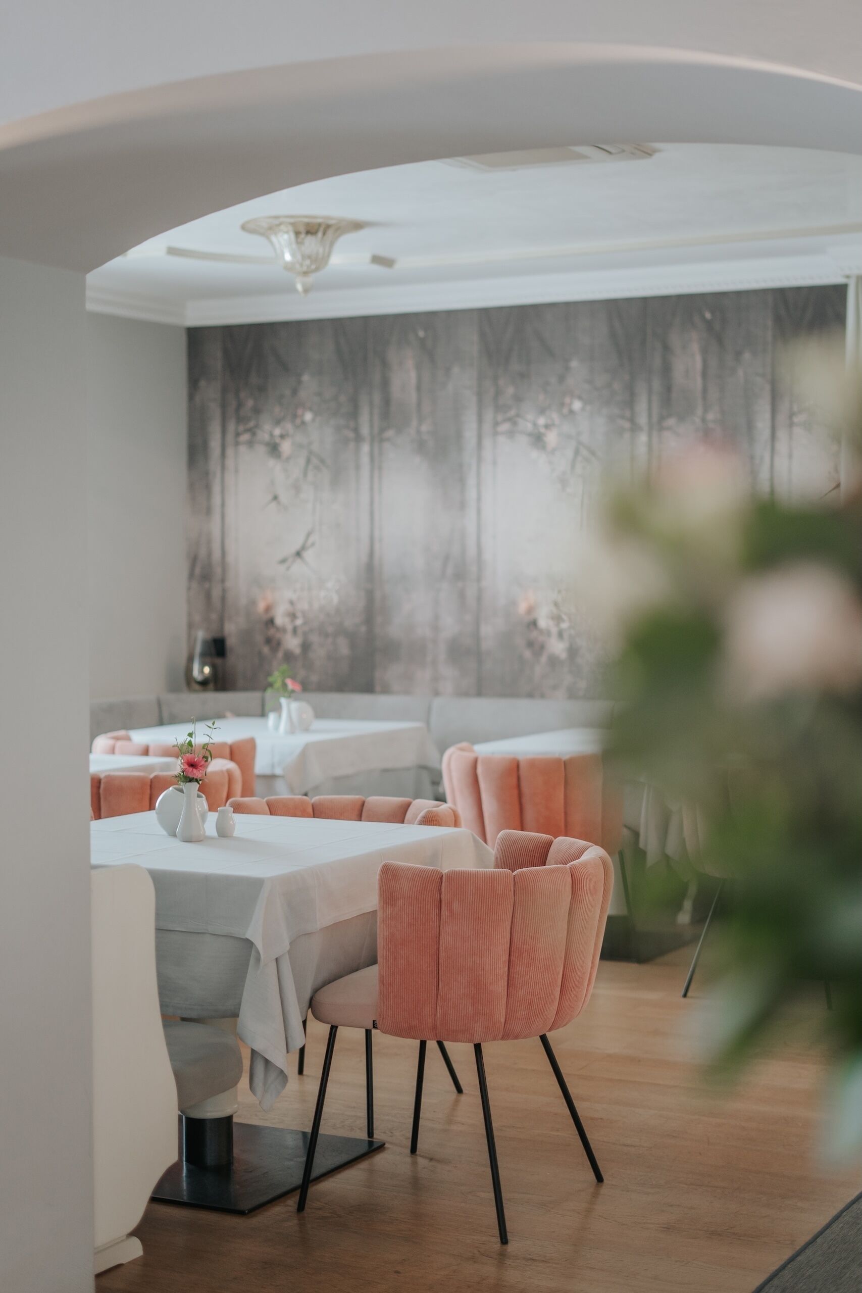 A modern dining area with tables and chairs, a ceiling light, and a wall with a textured design.