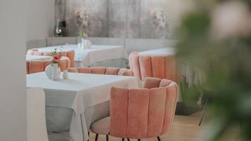 A modern dining area with tables and chairs, a ceiling light, and a wall with a textured design.