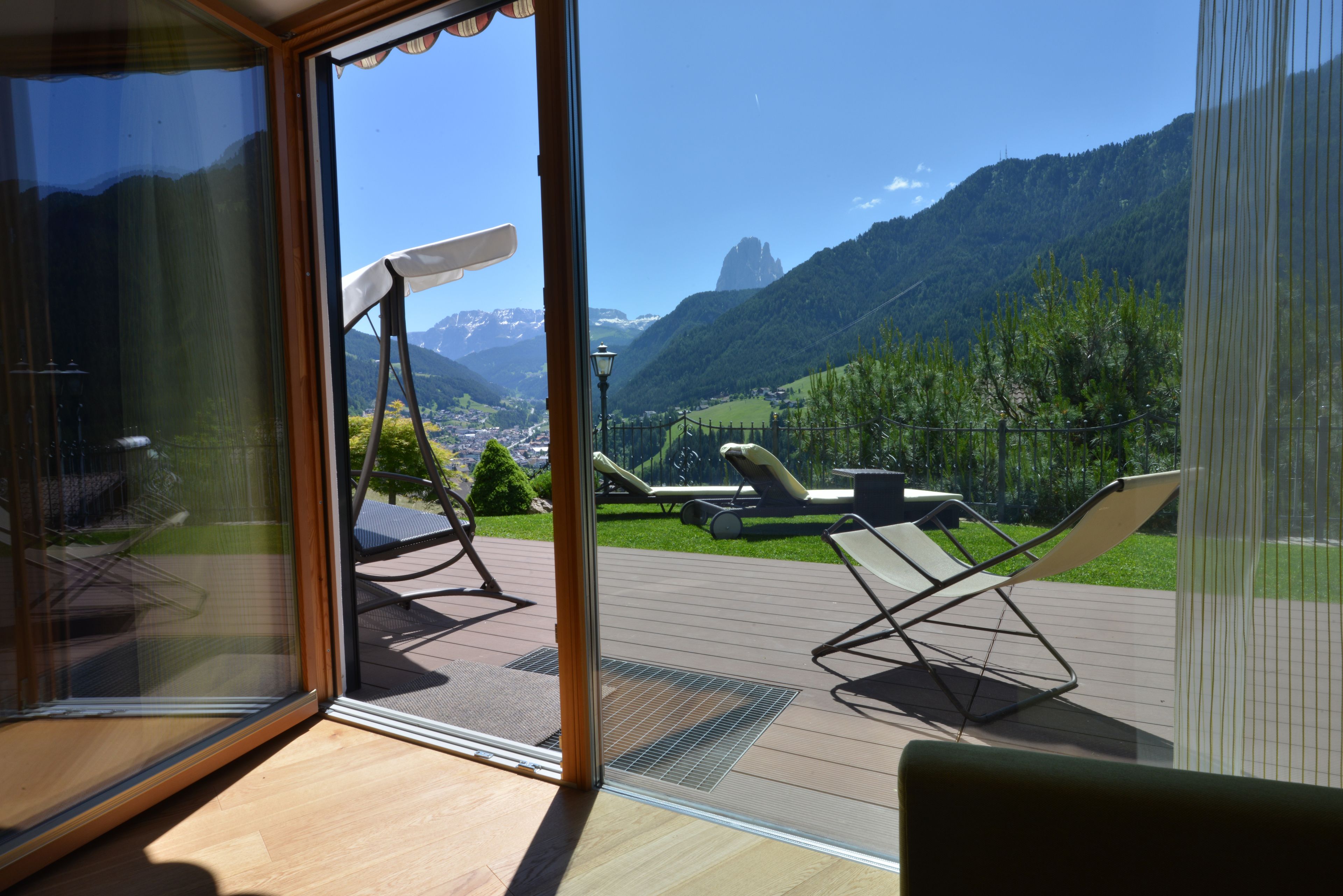 Un balcon offrant une vue sur un paysage montagneux, une terrasse en bois et du mobilier d’extérieur.