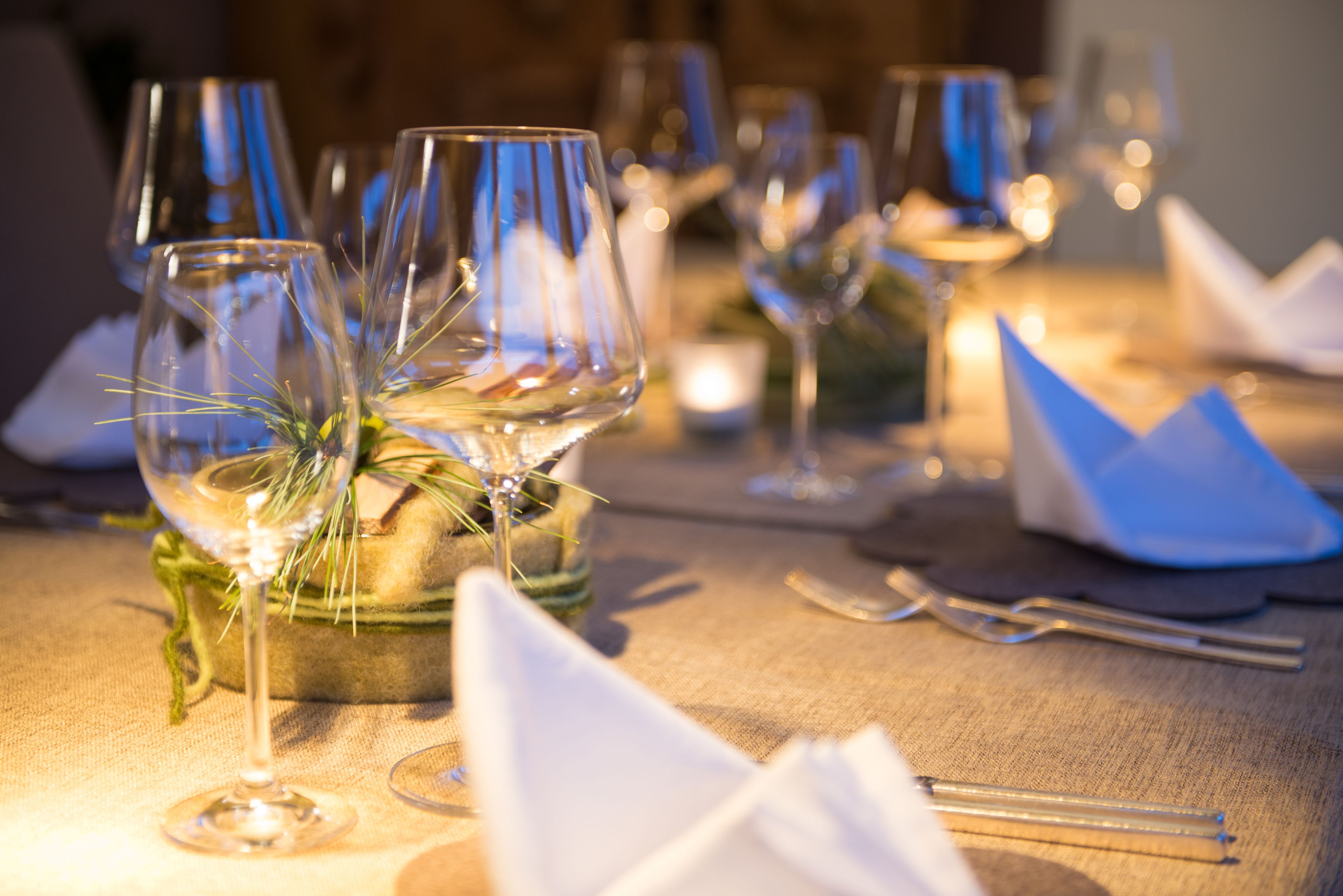 Una mesa servida con copas de vino, una vela y un centro de mesa decorativo.