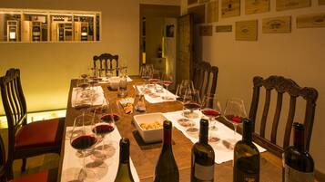Una mesa de comedor preparada con copas de vino, botellas y un bol de aperitivos.