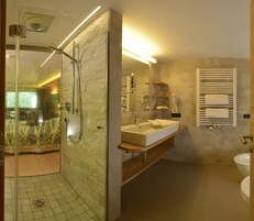 Un baño moderno con ducha de vidrio, tocador con lavabo y espejo, y un inodoro.