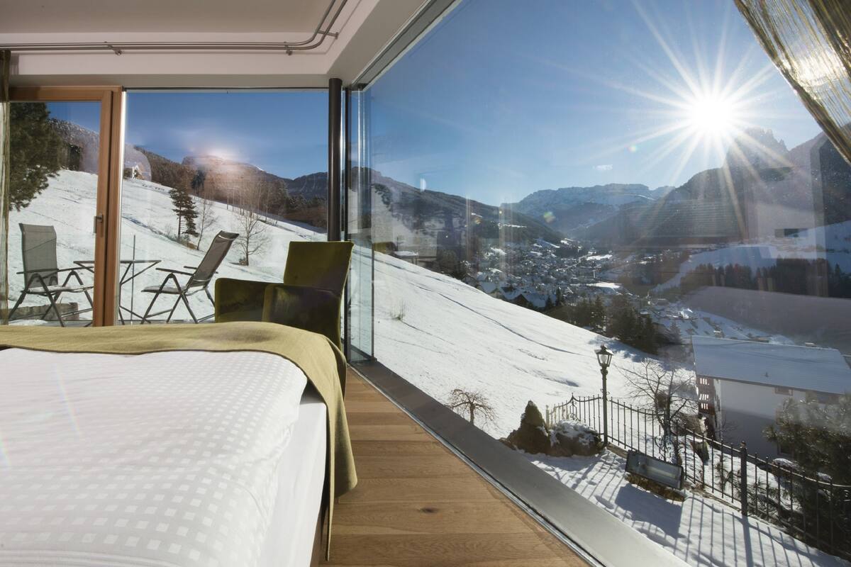 A bedroom with a large window overlooking a snowy mountain landscape.