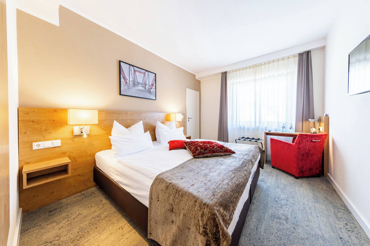 Een hotelkamer met een groot bed, nachtkastjes, een bureau en een stoel.