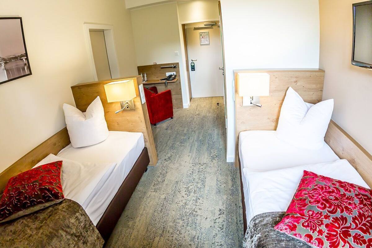 Een hotelkamer met twee bedden, een bureau, een stoel, een spiegel en een televisie.