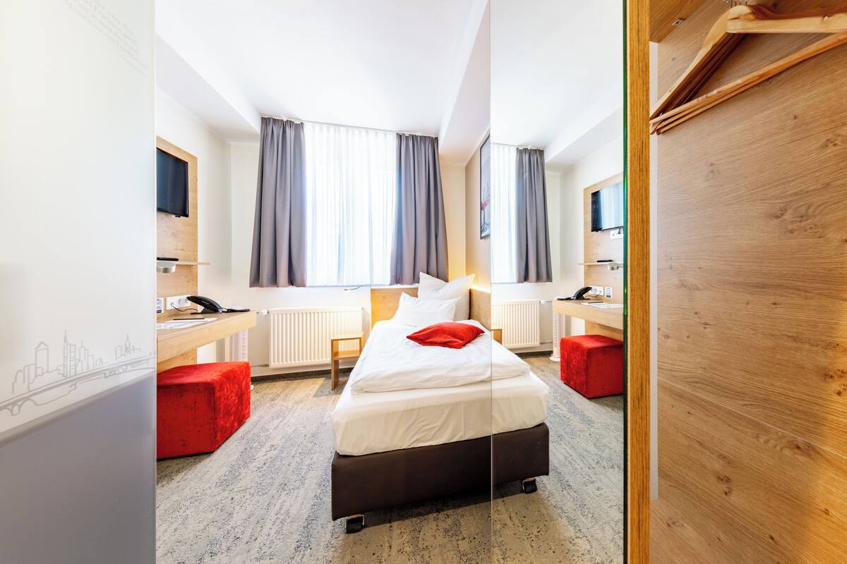 Een hotelkamer met een bed, een bureau, een stoel en een televisie.