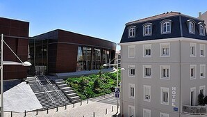 Un hôtel doté d’une façade moderne, d’une entrée bien visible et d’un parking avec un espace de stationnement abrité.