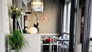 Un espace d’accueil d’hôtel au design moderne, comprenant un comptoir d’accueil, un coin salon avec des fauteuils et une grande fenêtre.