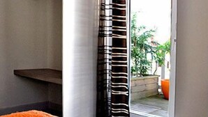 Une chambre avec un lit, une fenêtre ornée de rideaux à rayures et une vue sur l’extérieur.
