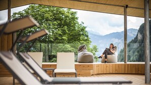 A modern outdoor lounge area with wooden flooring and seating, overlooking a mountainous landscape. -  Hotel Platz (Castelrotto)