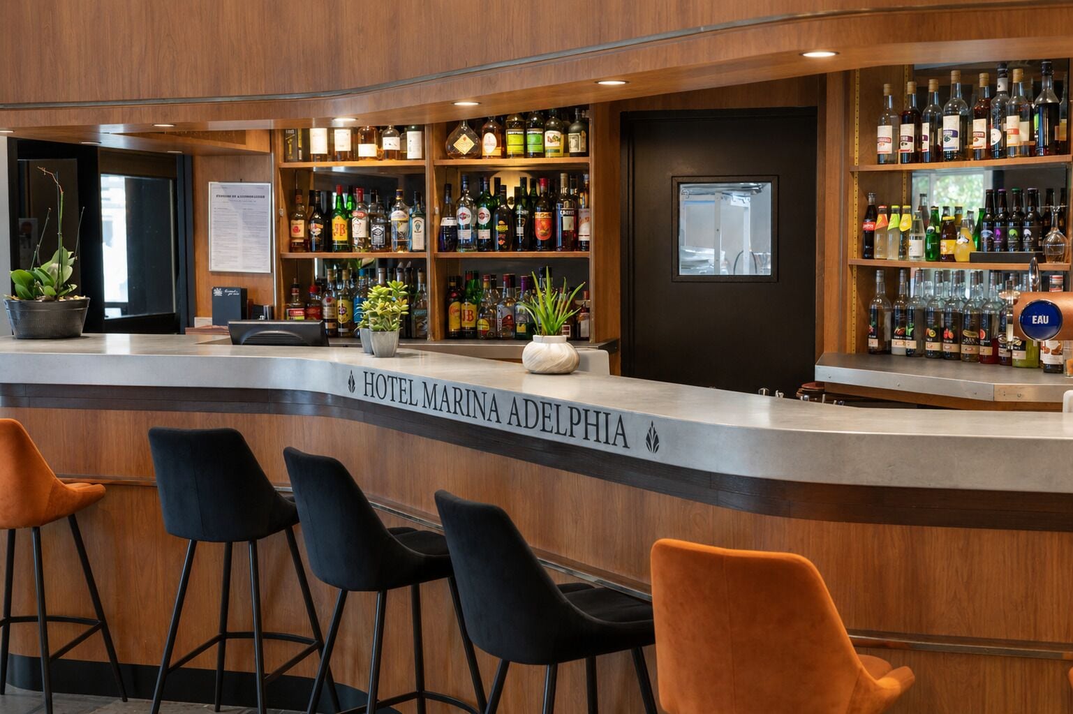 A bar area with a counter, bar stools, and shelves of liquor bottles.