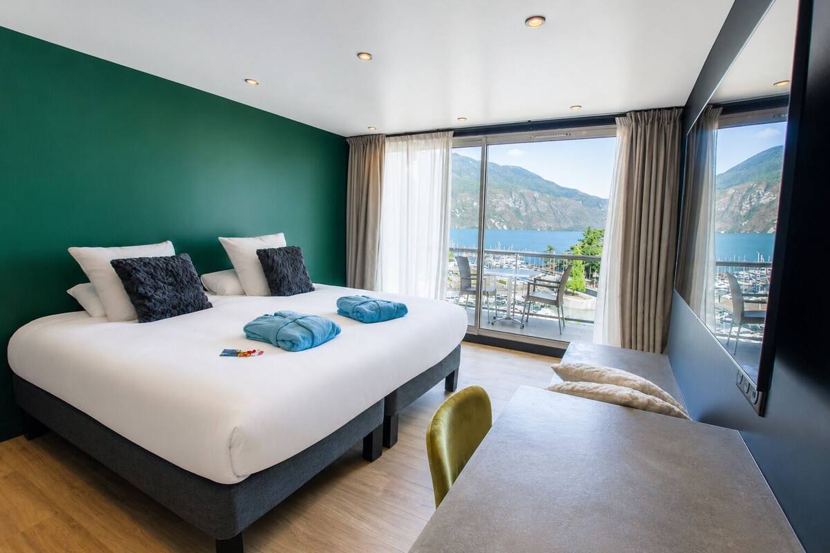 Een hotelkamer met een groot bed, een eettafel en uitzicht op zee.