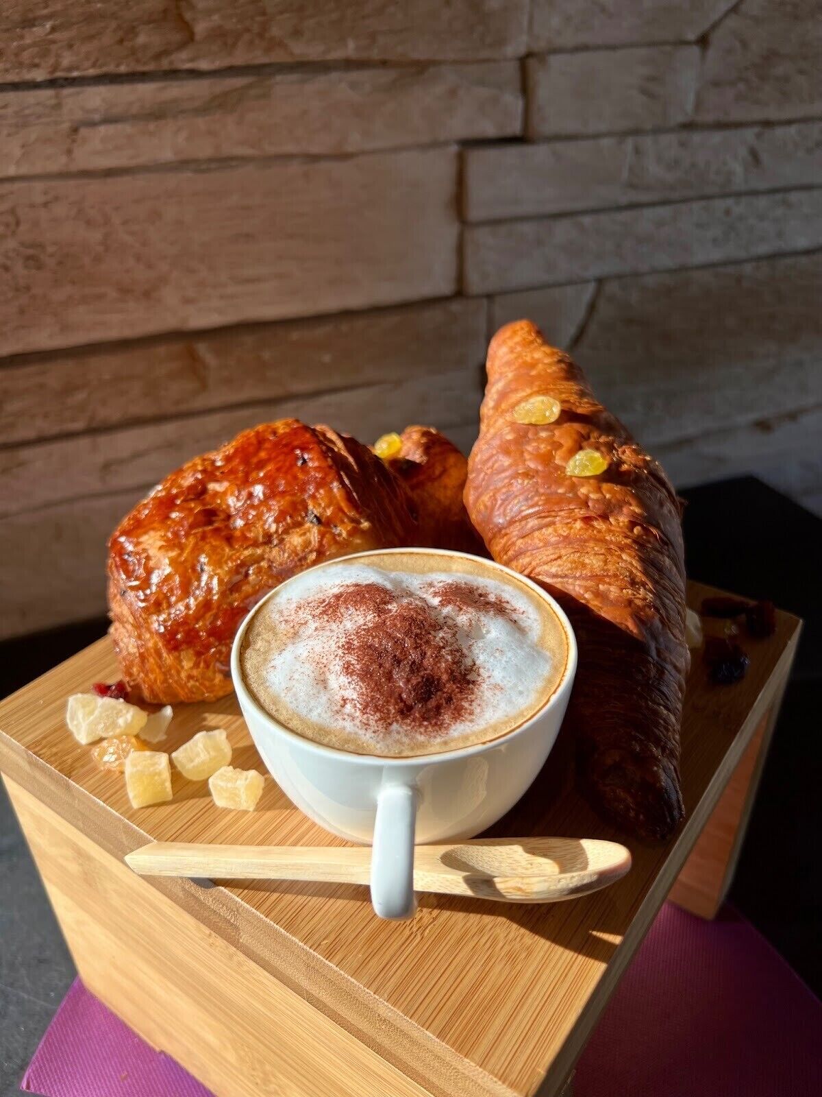 Une table en bois avec une tasse de café et deux pâtisseries.