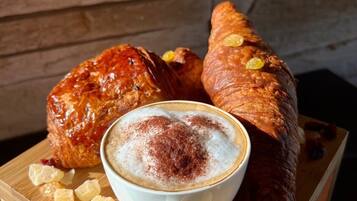 Une table en bois avec une tasse de café et deux pâtisseries.